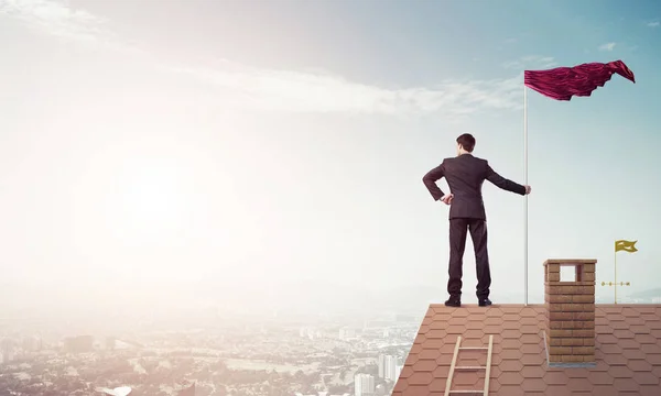 Businessman standing on house roof — Stock Photo, Image