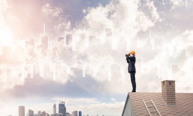 Takım elbise ve kask çatıda genç işadamı 