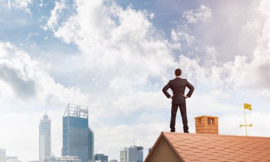 evin çatısında duran işadamı 