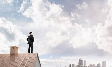 evin çatısında duran işadamı 