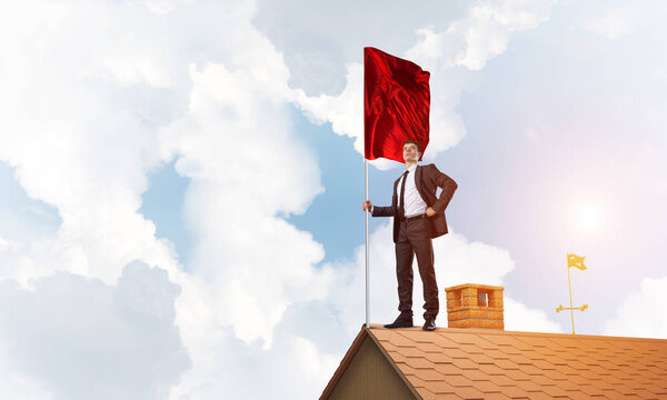 businessman standing on house roof 