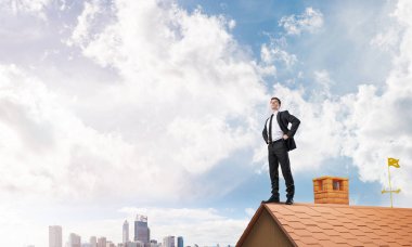 evin çatısında duran işadamı 