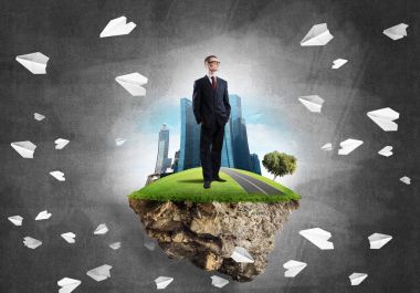 Yeşil yüzen ada üzerinde duran işadamı