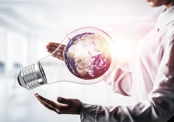Бизнесмен держит лампочку с Землей — стоковое фото