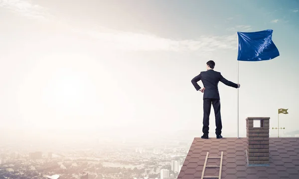 Businessman standing on house roof — Stock Photo, Image