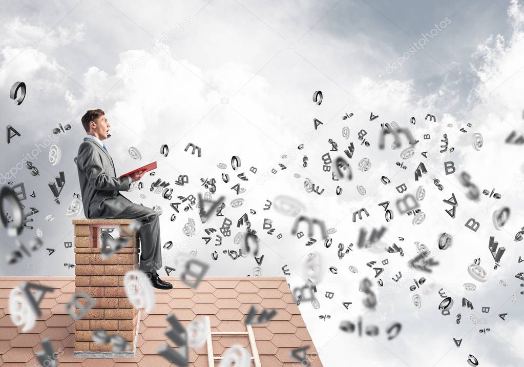 Man on brick roof reading book