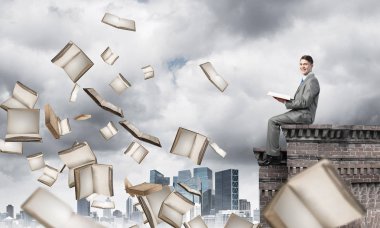 Elinde kırmızı kitap ile kenar binasında oturan genç işadamı
