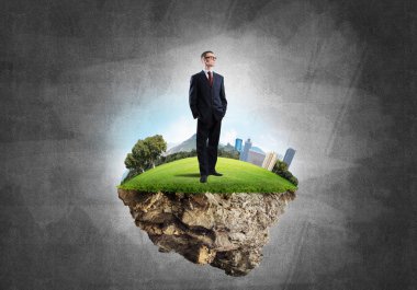 Yeşil yüzen ada üzerinde duran işadamı