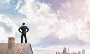 Evin çatısında duran genç işadamı 