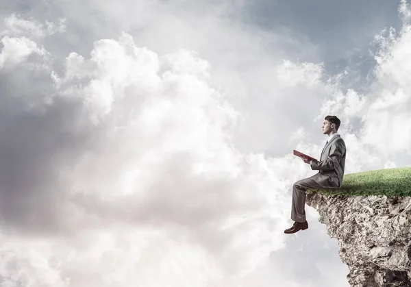 Businessman sitting on edge of cliff — Stock Photo, Image