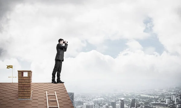 Biznesmen, stojąc na dachu domu — Zdjęcie stockowe