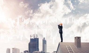 Takım elbise ve kask çatıda genç işadamı 