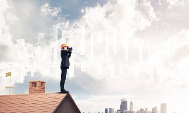 Takım elbise ve kask çatıda genç işadamı 