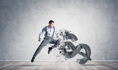 Genç öfkeli işadamı ile çökmesini ve atlama tekme boş beton odada Doları sembol taş