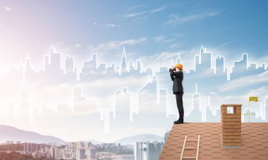 Takım elbise ve kask çatıda genç işadamı 