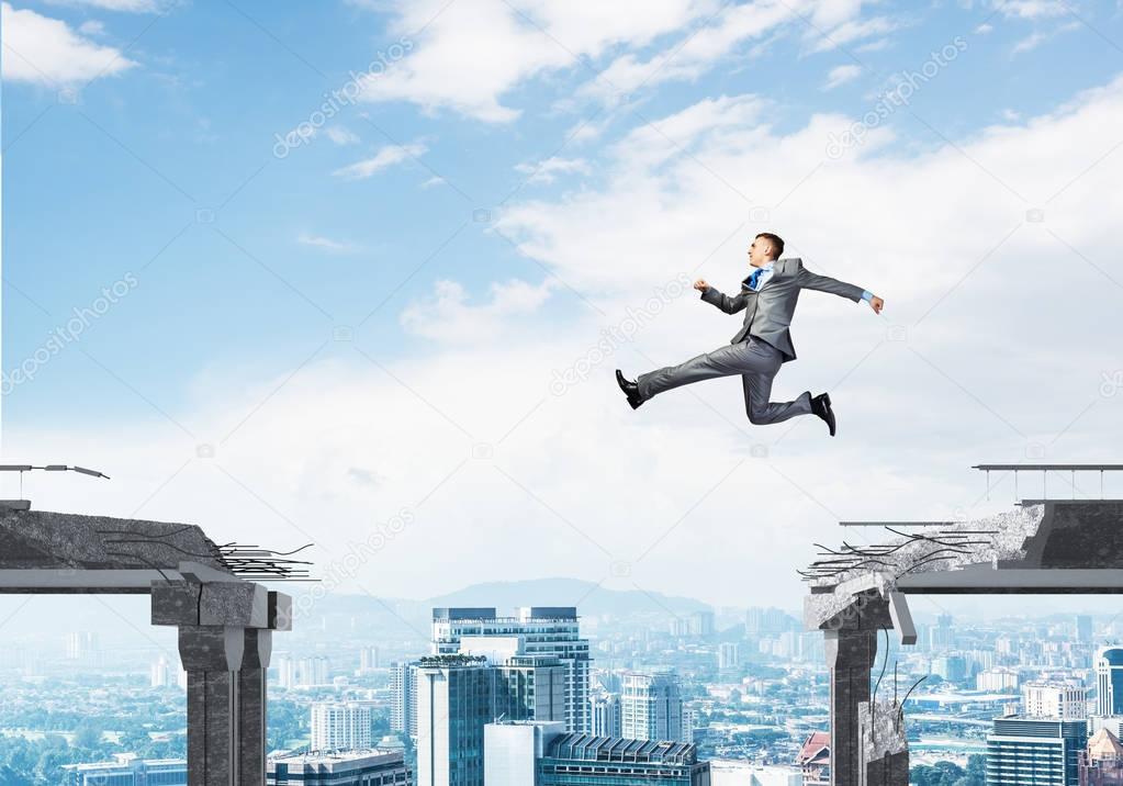 Businessman jumping over gap in concrete bridge as symbol of overcoming challenges with cityscape on background, 3D rendering