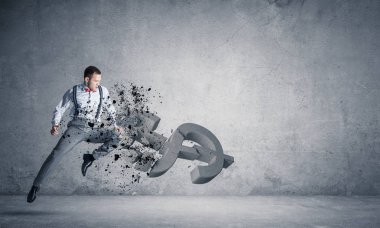 Genç öfkeli işadamı ile çökmesini ve atlama tekme boş beton odada Doları sembol taş