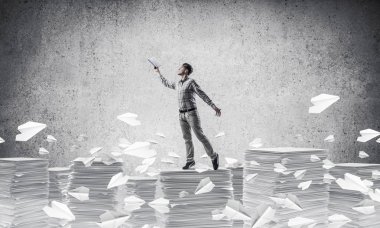 Rahat kıyafet kağıt uçan arasında duran el kitabı ile uydurarak erkekte gri arka plan ile uçak. Karışık teknik.