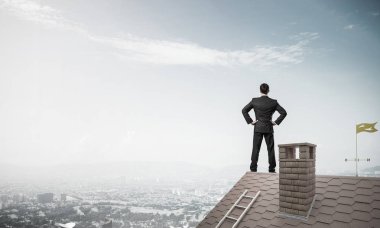 Evin çatısında duran genç işadamı 