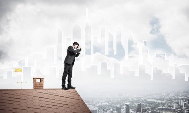 Çatıda duran ve dürbünle bakan bir iş adamı. Karıştırdı.