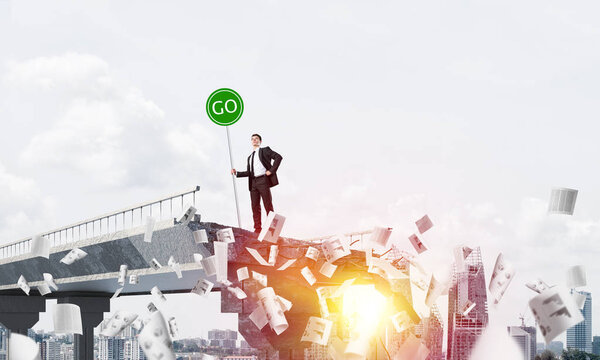 Confident businessman in suit holding green go sign while standing among flying papers on broken bridge with cityscape and sunlight on background. 3D rendering.