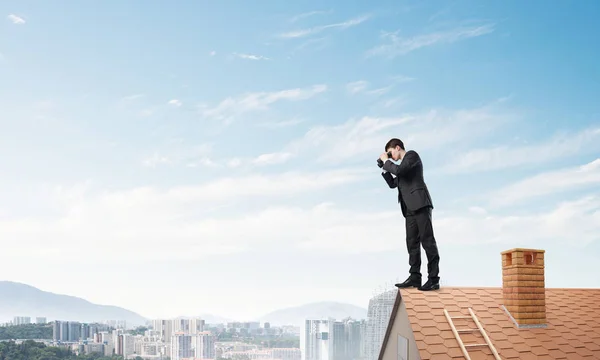 Hombre de negocios de pie en el techo de casa — Foto de Stock