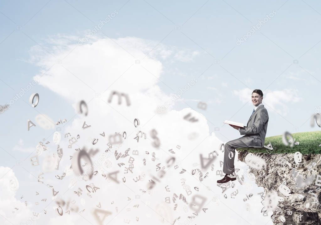 businessman sitting on edge of cliff 