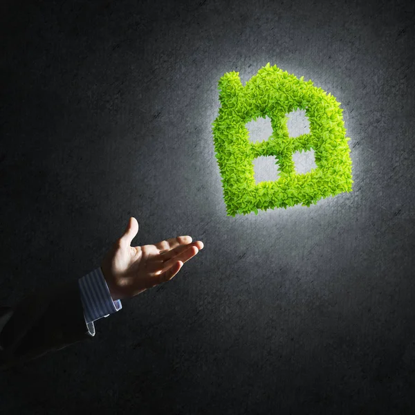 businessman hand and green house icon