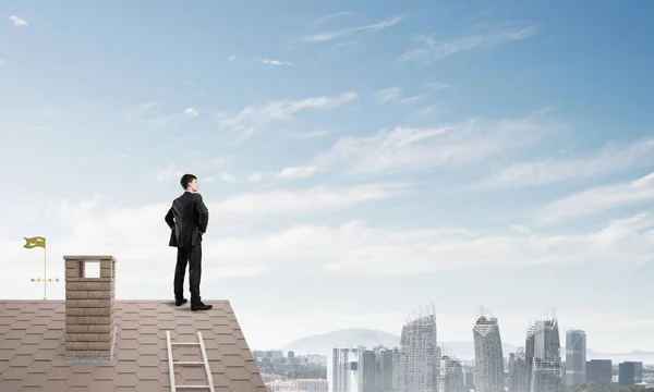 Hombre de negocios de pie en el techo de casa — Foto de Stock
