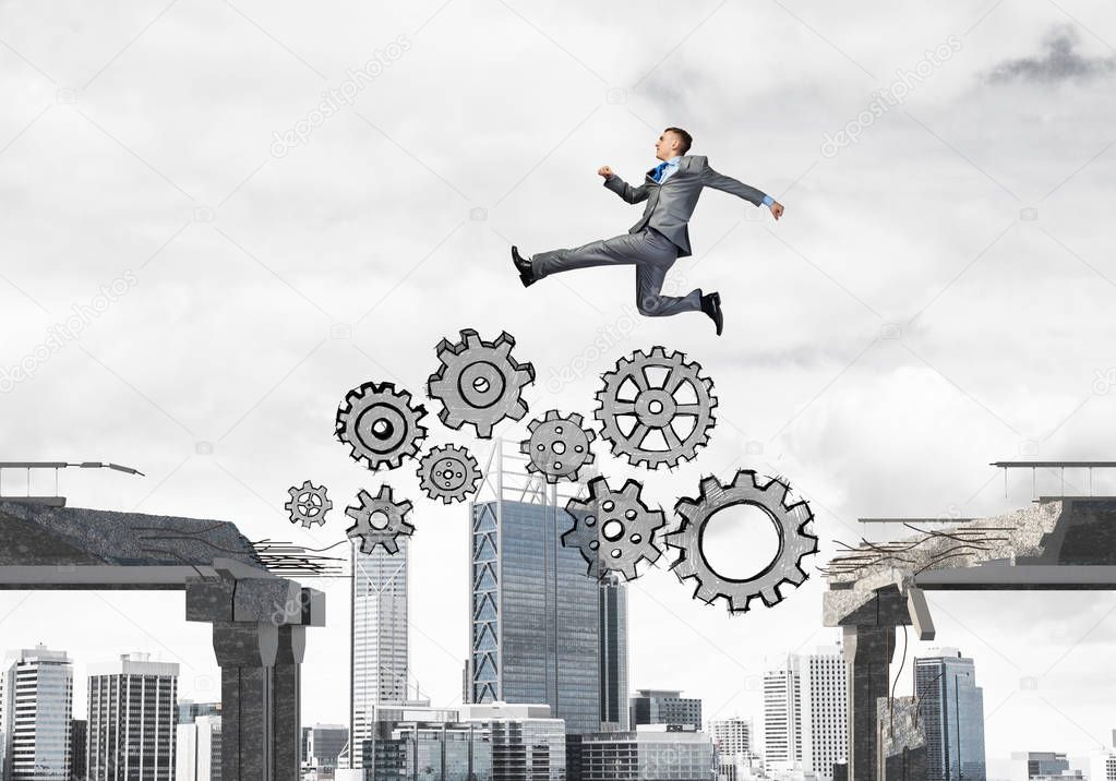 Businessman jumping over gap with gear mechanism in concrete bridge as symbol of overcoming challenges with cityscape on background, 3D rendering