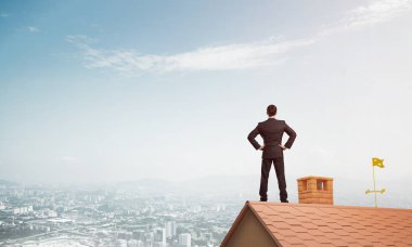 businessman standing on house roof clipart