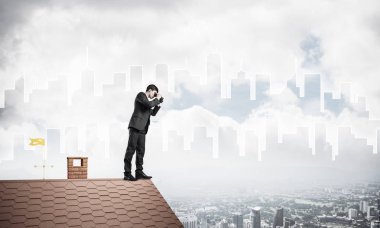 Çatıda duran ve dürbünle bakan bir iş adamı. Karıştırdı.