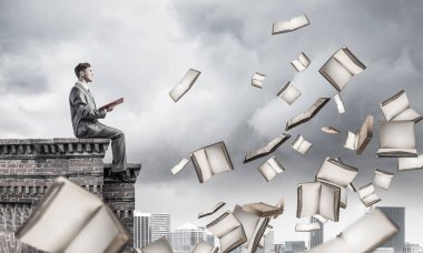 Elinde kırmızı kitap ile kenar binasında oturan genç işadamı