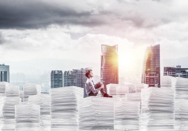 Düşünceli işadamı uzak belgeler cityscape ve arka plan üzerinde güneş ışığı ile yığını üzerinde otururken arıyorum. Karışık teknik.