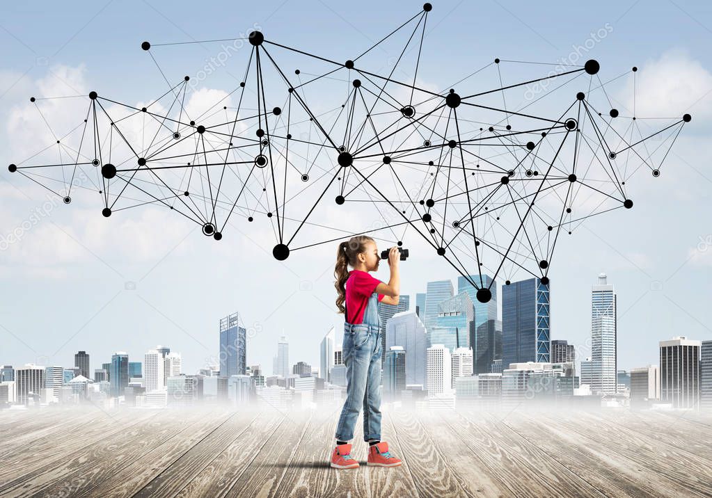 Cute girl is standing on wooden floor and looking through binoculars. Concept of social wireless connection and internet 