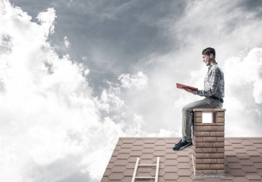 Elinde kırmızı kitap ile evin baca rahat oturan genç adam