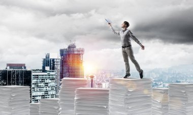 Rahat kıyafet ise cityscape belgelerle yığını üzerinde duran ve arka plan üzerinde güneş ışığı el kitabı ile uydurarak adam. Karışık teknik.