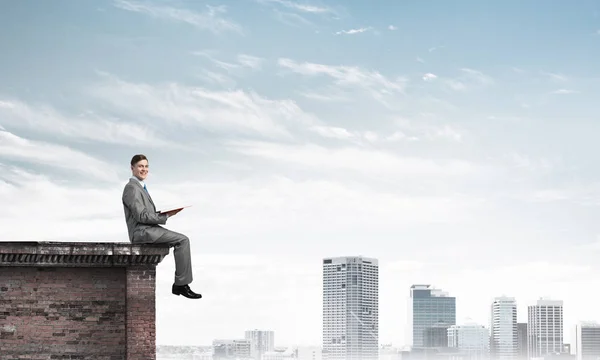 Jovem empresário sentado no topo da construção — Fotografia de Stock