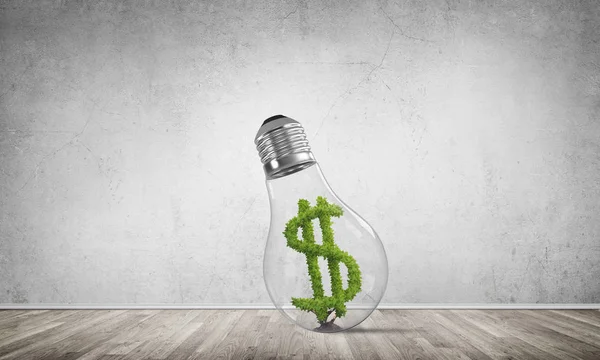 Glass lightbulb with green dollar symbol inside in empty room with grey wall on background