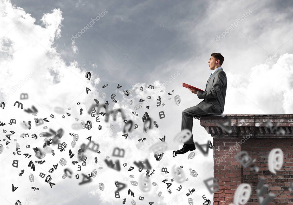 Young businessman sitting on building top