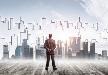 İşadamı arkasını dönüp modern iş merkezinin siluetine bakıyor.