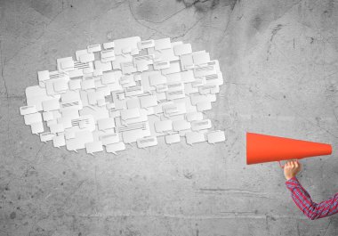 Beton arka planda kırmızı borazan tutan bir kadın eli