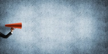 İşkadını beton arka planı kırmızı kağıt trompet tutan eli