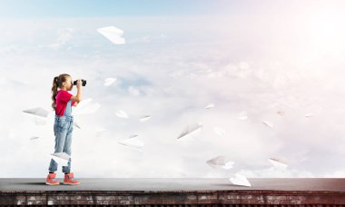 Dürbünle bakan, okul çağındaki sevimli kız çatıyı inşa ediyor.