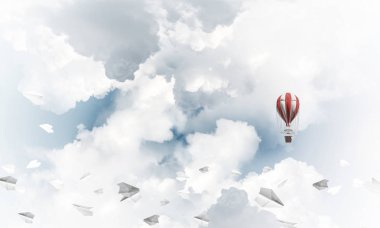 Renkli aerostat kağıt uçaklar arasında ve mavi bulutlu gökyüzü üzerinde uçan. 