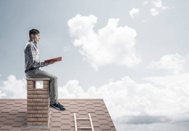 Elinde kırmızı kitap ile evin baca rahat oturan genç adam