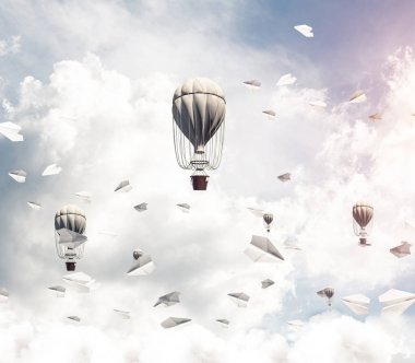 Renkli aerostats kağıt uçaklar arasında ve mavi bulutlu gökyüzü üzerinde uçan. 3D render.