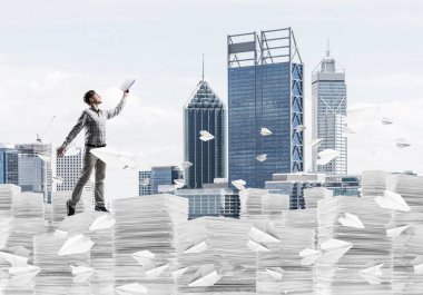 Adam arka plan üzerine karışık teknik kağıt uçaklar ile cityscape uçan arasında duran el kitabı ile uydurarak giyim