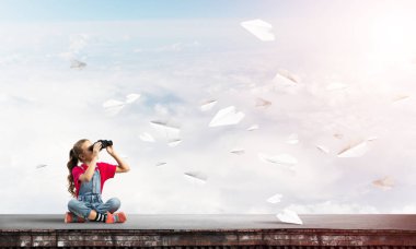 Dürbünle bakan, okul çağındaki sevimli kız çatıyı inşa ediyor.