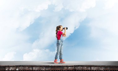 Dürbünle bakan, okul çağındaki sevimli kız çatıyı inşa ediyor.